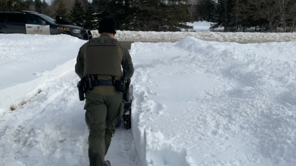 After a significant snowfall in Kawartha Lakes, Ont., an Ontario Provincial Police officer clears snow from a senior's residence. (OPP Central Region/Twitter)