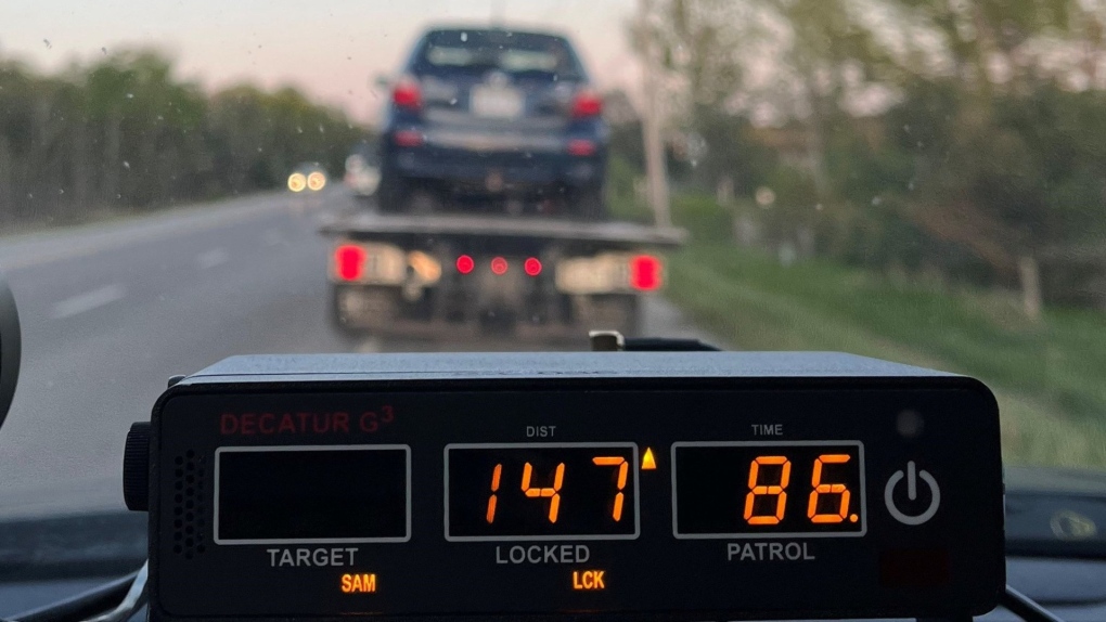 A vehicle is loaded onto a tow truck as a police radar device shows a speed of 147km/h in Wyebridge, Ont., on Mon., May 29, 2023. (Central Region OPP/Twitter)