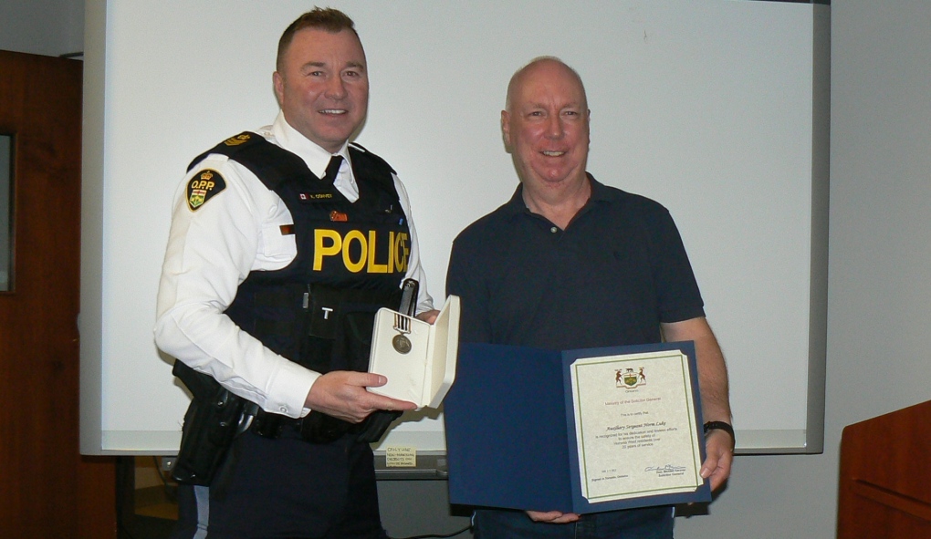 Kevin Convey, Huronia West OPP’s operations manager, presents Auxiliary Constable Norm Luke with a 20-year service letter of recognition and medal. (Provided/Huronia West OPP)